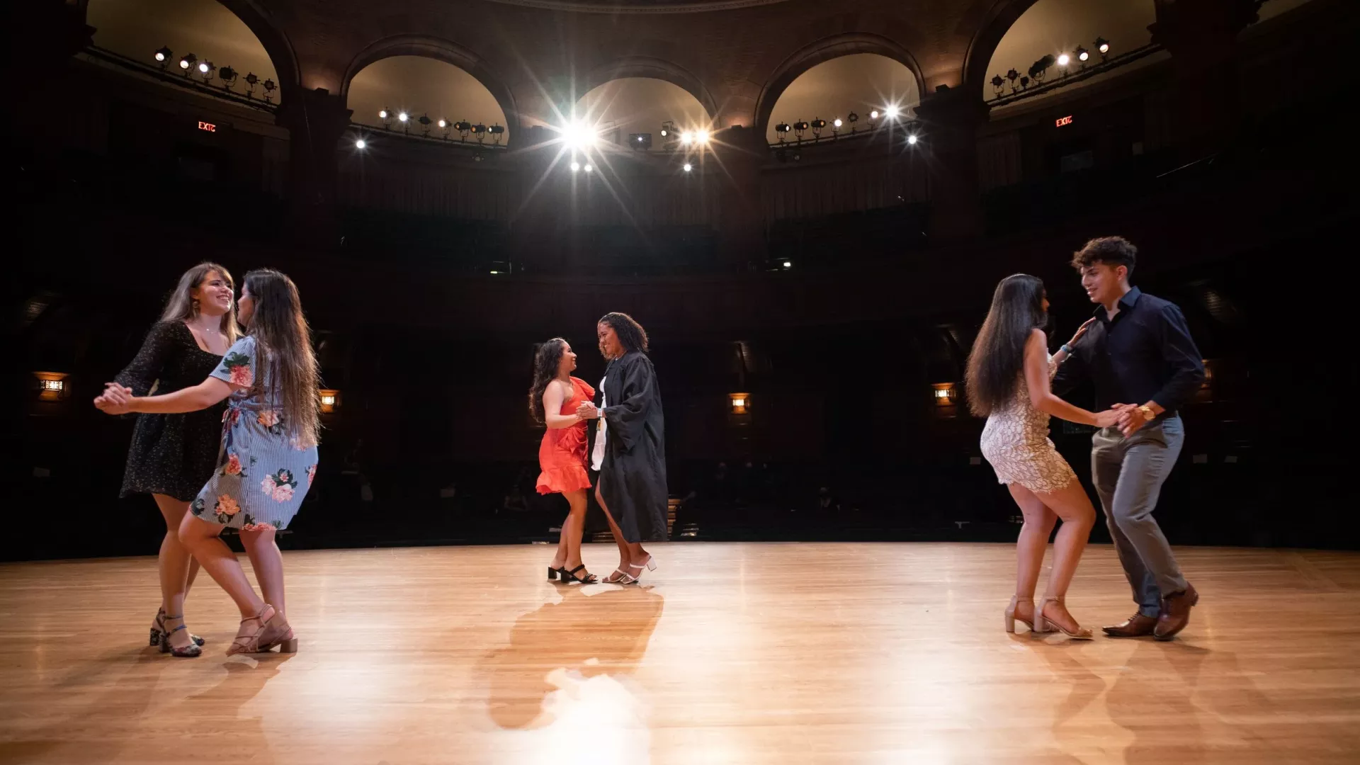 Students dance on stage during Latinx graduation.