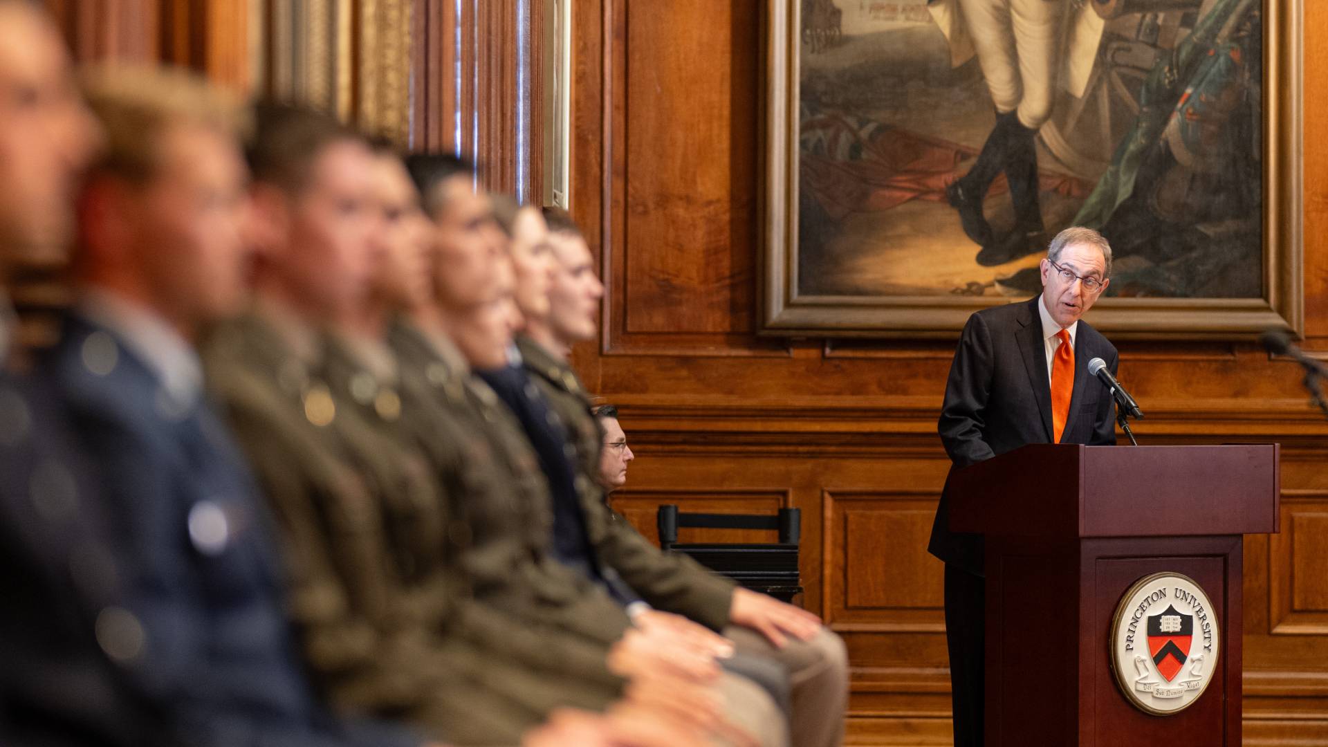 President Eisgruber speaks to officers in the Faculty Room with George Washington's portrait behind him