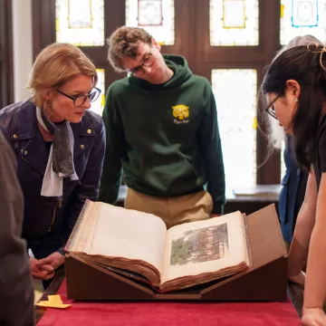 Students and a professor look at a book in Special Collections.