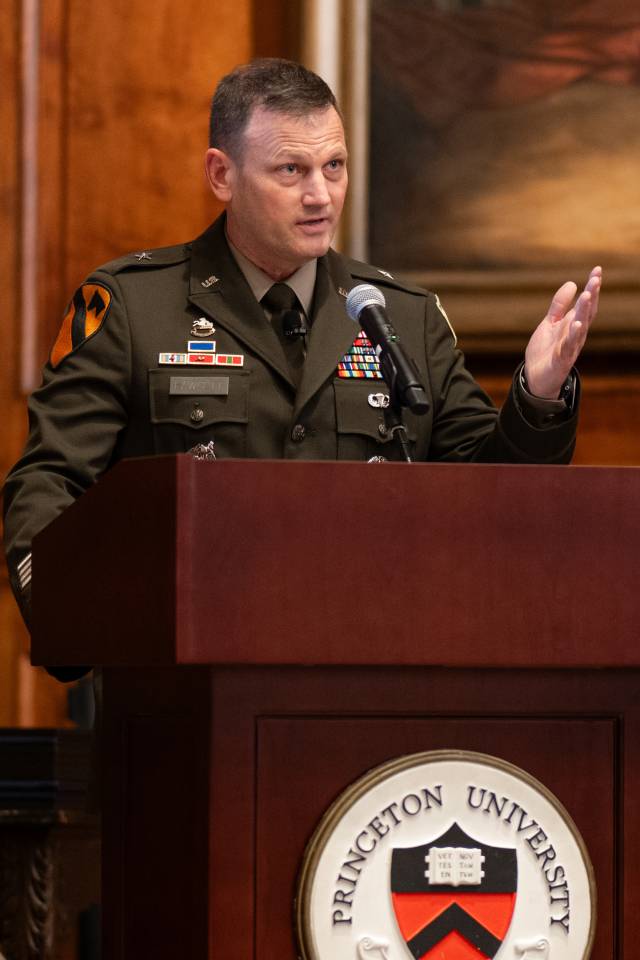 Brig. Gen. Fawcett raises hand for emphasis while speaking from podium